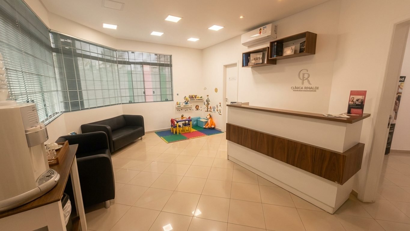 Recepção da Clínica Rinaldi com cantinho infantil e balcão com o logotipo